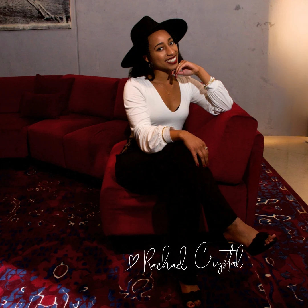 RAINA's founder Rachael sits on a couch wearing Ebony Crown satin lined wool fedora.
