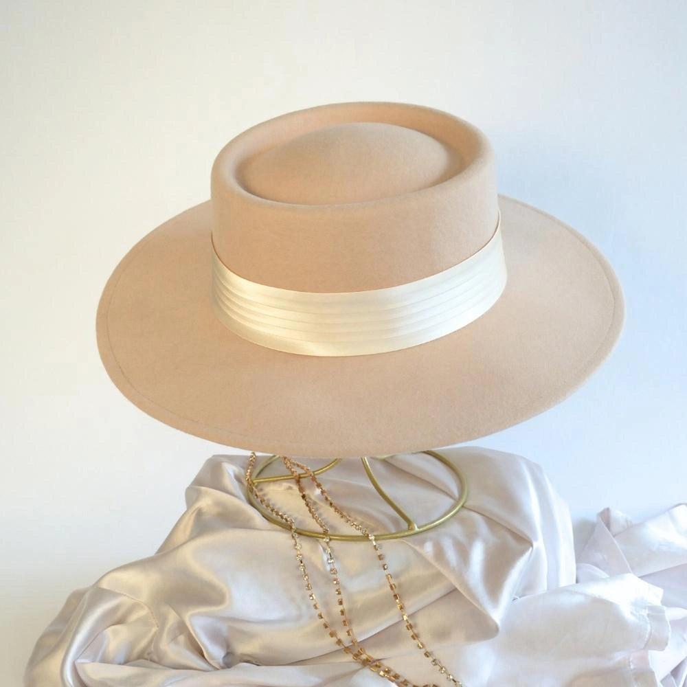 A front view of the beige beauty wool satin lined boater hat with the ivory satin hat band.