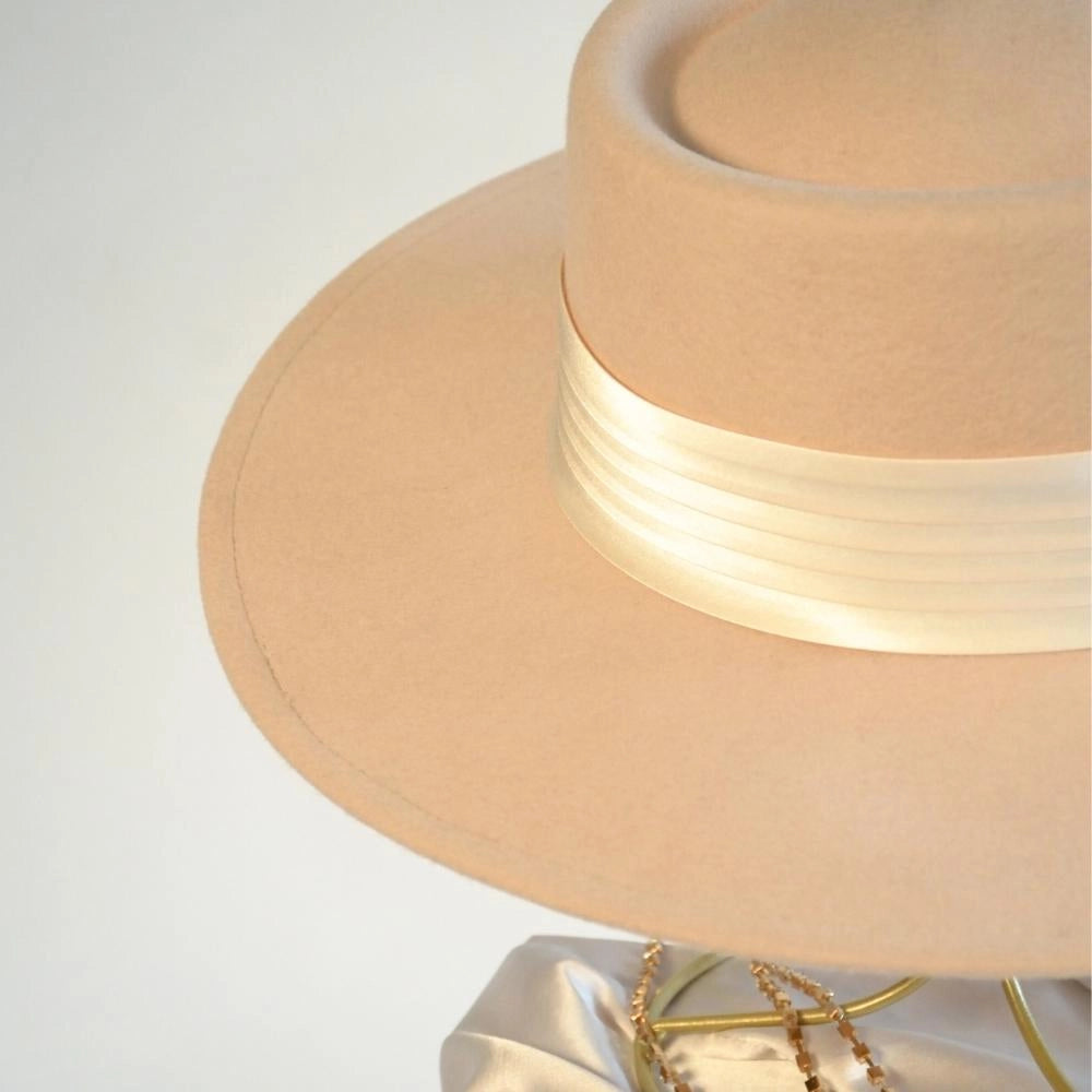 A close up of the beige beauty wool boater hat with the ivory satin hat band.