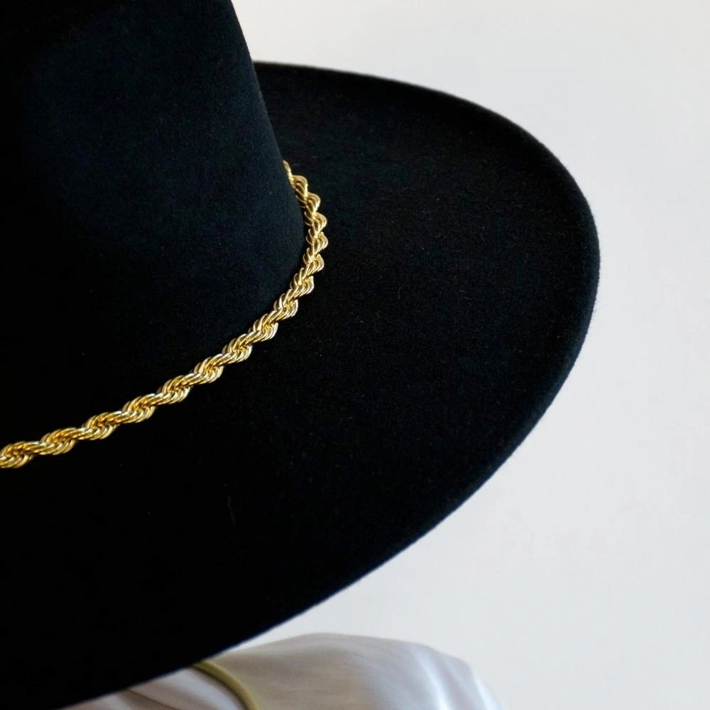 A close up of the black wool fedora with the 18k gold twist hat band.