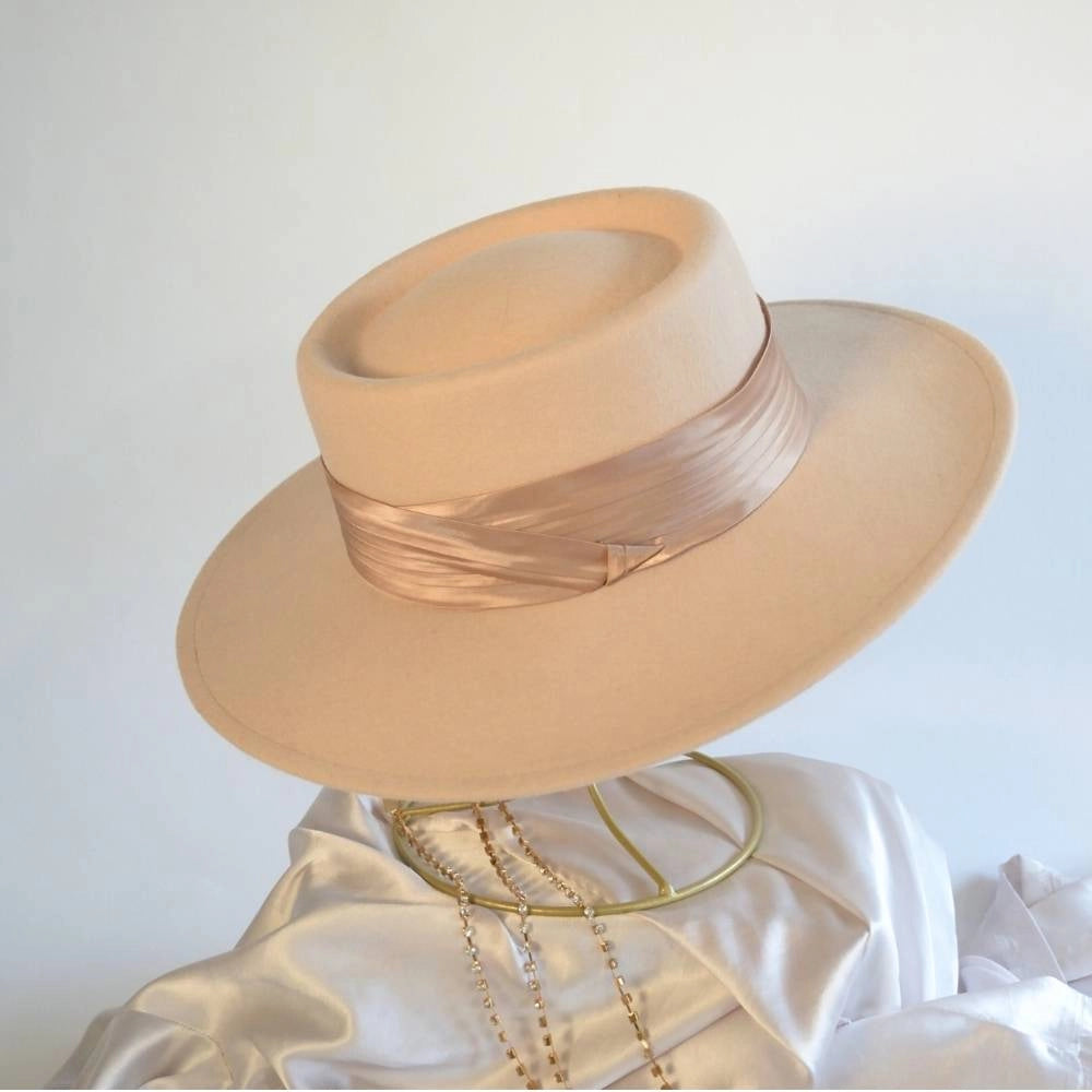 A side view of the beige beauty boater hat with the caramel satin hat band.