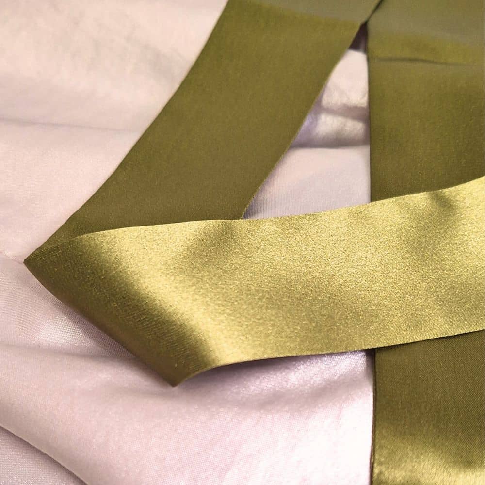 A close up view of the olive green mulberry silk ribbon used to accessorize our straw beach hats.