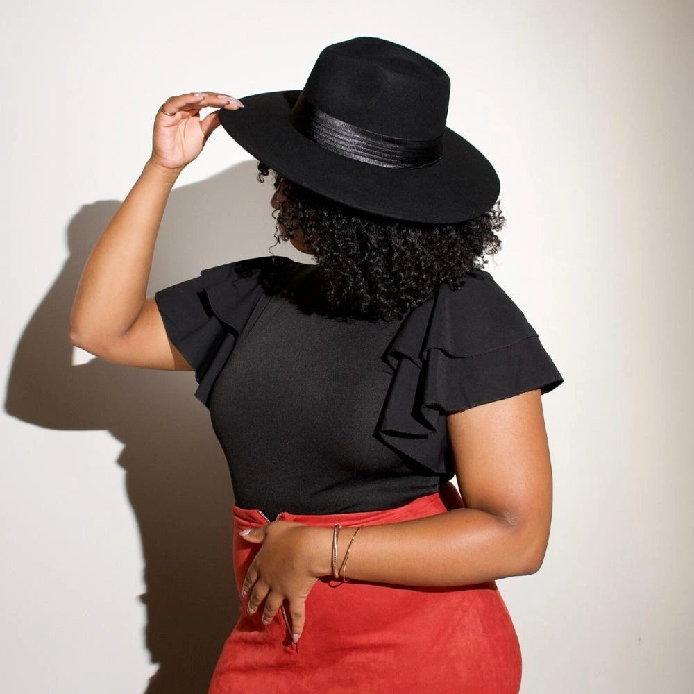 A model turns to the side wearing the satin lined black fedora, Ebony Crown, with the Midnight Satin hat band.