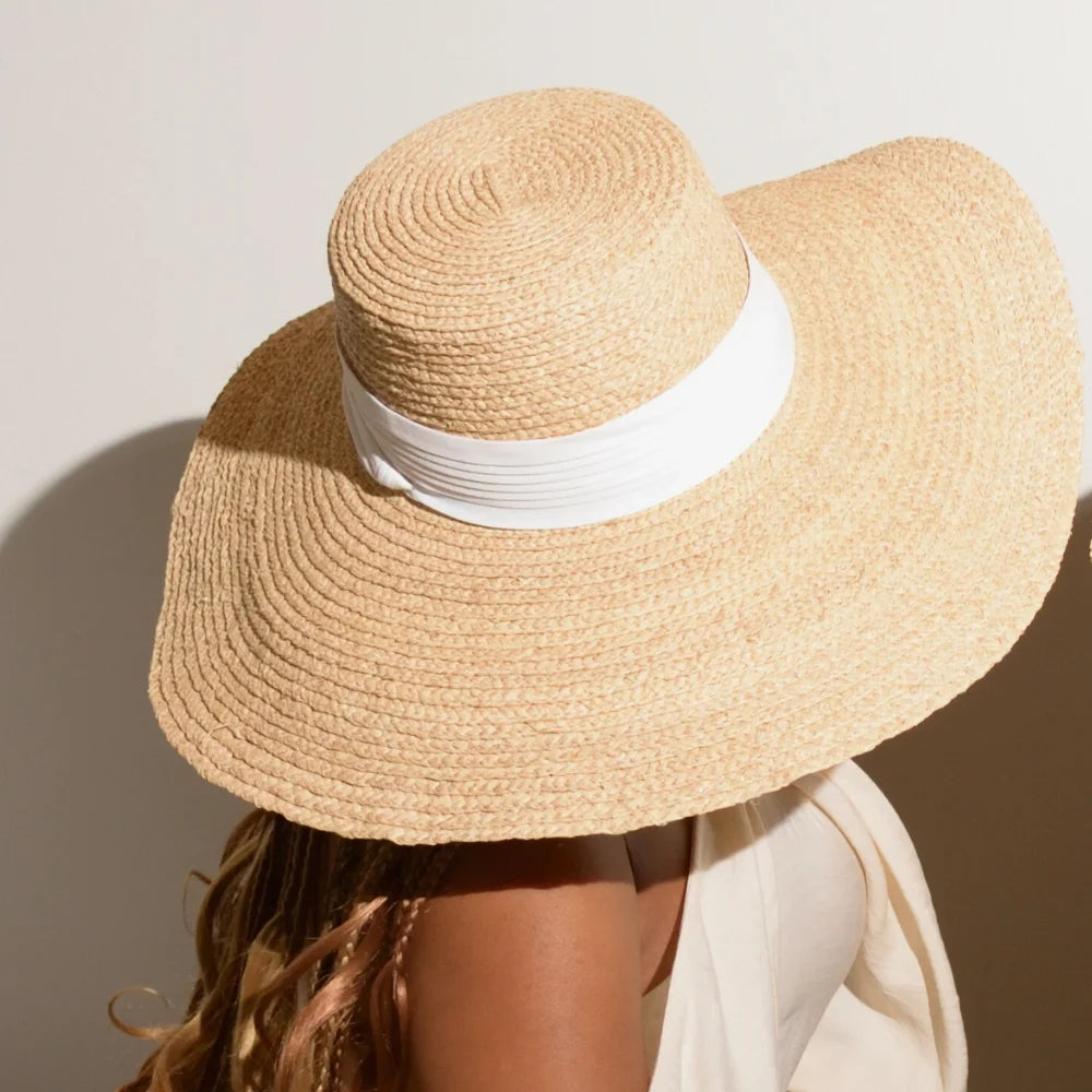 A model wears the pearl white hat band on the raffia straw satin lined hat.