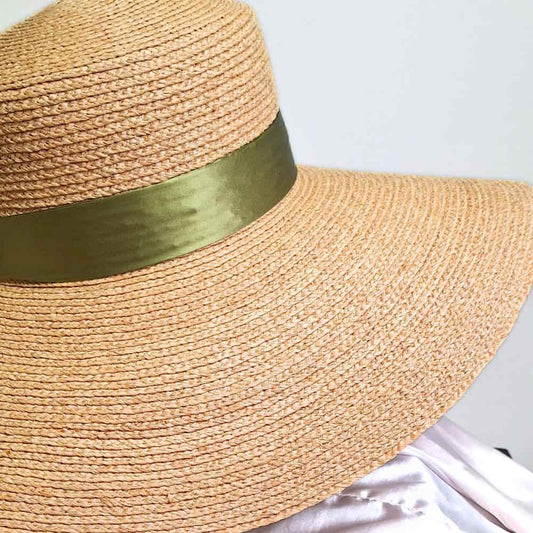 A side view of our satin lined sun straw hat with the 100% mulberry silk olive green bow.