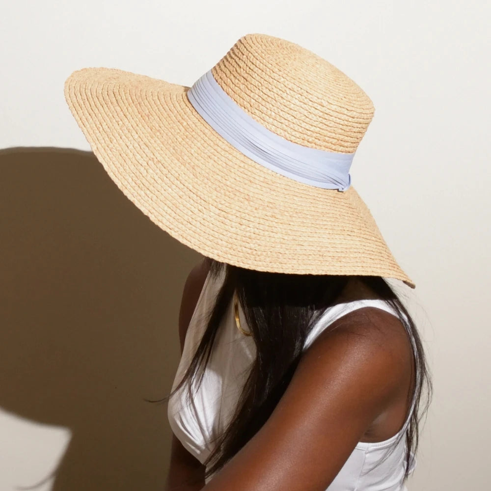 A model wears the Sunlit Dream Raffia Sunhat with a Sky Blue hat band.