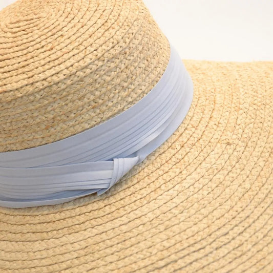 A close up image of the Sunlit Dream Raffia Sun Hat with the Sky Blue hat band.