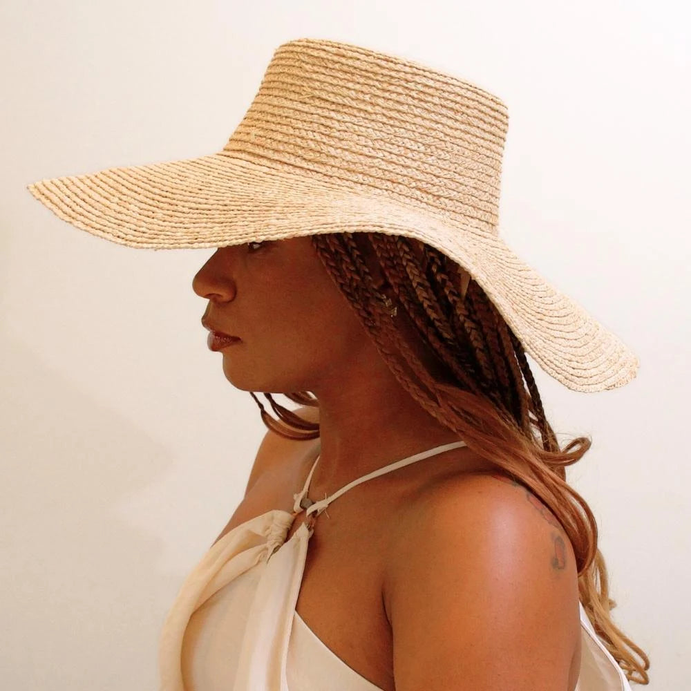 Second side view of model wearing sunlit dream satin lined wide brimmed raffia sun beach hat.